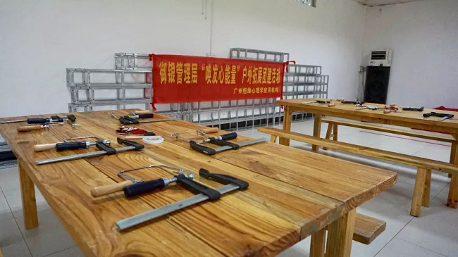 　測(cè)試不是目的，在香草拓展基地的冠軍營(yíng)地，培訓(xùn)機(jī)構(gòu)還特別請(qǐng)來(lái)了黃大仙為大家解讀迷津，讓參訓(xùn)的管理人員重新認(rèn)識(shí)心底的自己，同時(shí)理解溝通中可能出現(xiàn)的障礙，與此同時(shí)，還借助測(cè)試引導(dǎo)管理人員轉(zhuǎn)換角度、換位思考，借此提高溝通的效能。不僅如此，黃大仙還在介紹過(guò)程中為參訓(xùn)人員提供了一些提升管理的溝通小秘籍。     經(jīng)歷匠人精神     　　沒(méi)有真正的經(jīng)歷，又談何真正的理解與認(rèn)識(shí)。管理人員來(lái)自不同的部門(mén)、不同的領(lǐng)域，為了加深理解與認(rèn)識(shí)，培訓(xùn)進(jìn)入了第二個(gè)環(huán)節(jié)——體驗(yàn)?zāi)舅嚬ぷ鞣?。每人一個(gè)F夾、一把手持鋸，一到兩塊木板、幾幅看似有些朦朧的造型圖、鉛筆、剪刀、砂紙，還有作品任務(wù)書(shū)，工作坊正式啟動(dòng)。